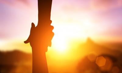 Helping hand with a sunset background.