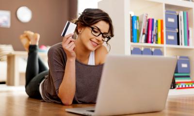 Woman lying on the floor with her laptop smiling having made an online sale