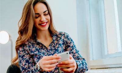 A lady sat down using a smart phone to contact her customers