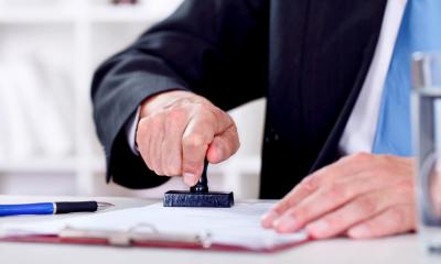 A man wearing a suit and tie putting a stamp on a piece of paper