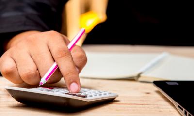 A mans hand using a calculator on a desk