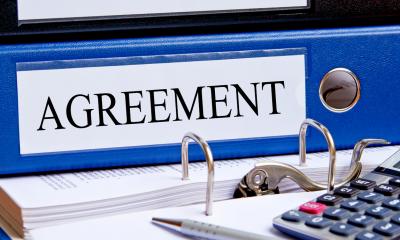 A blue folder on a desk with the word agreement on it