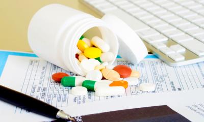 A collection of medical pills spilling out of a bottle onto a desk
