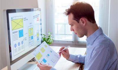 A website designer reads a client specification document and sketches - wireframe layout design for responsive web content