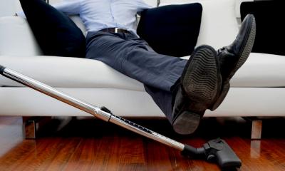 a businessman lifts his feet so that the floor can be vacuumed