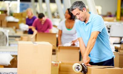 A group of people in a warehouse packing cardboard boxes