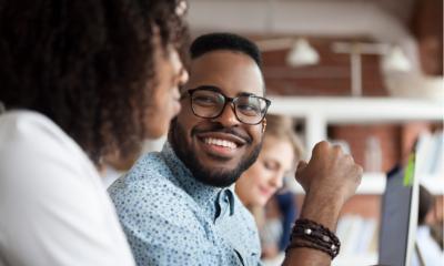 Close up of smiling African American employee look at female colleague chatting in office