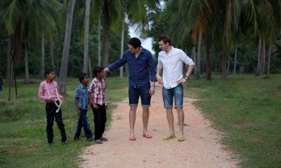 The founders of Gandys with children on a dirt path with palm trees in the background