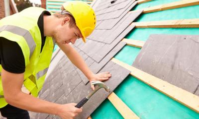 Roofer fixing lead tiles on slanted roof