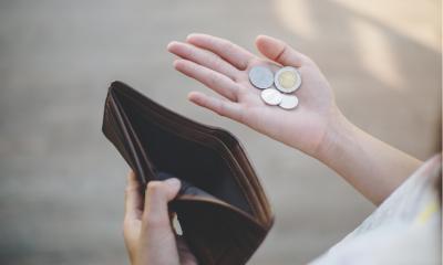 Hands holding an empty wallet and a handful of change