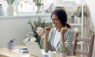 Woman looking excitedly at her laptop and cheering