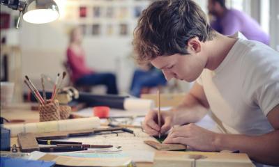 Sign writer working at his busy desk under a lamp