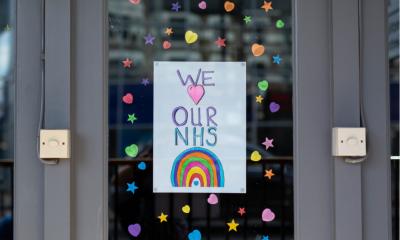 We love our NHS sign with rainbow and pink heart banner hanged on the window decorated with colorful stickers on display of closed restaurant