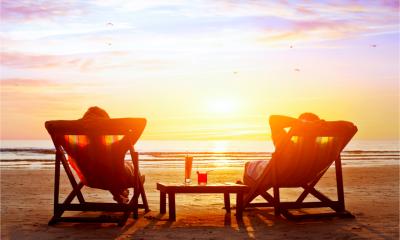 Two employees make the most of a holiday by sitting in a deckchair drinking cocktails