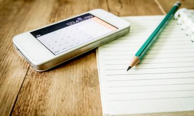 Phone calculator next to a notepad and pencil