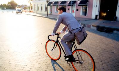 Businessman riding bicycle to work on urban street in the morning