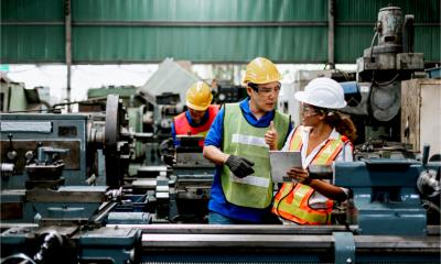 Professional engineers wearing PPE with tablet working machine lathe metal, in heavy industry in factory.
