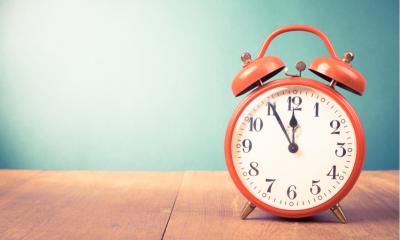 Retro red alarm clock with five minutes to twelve o'clock