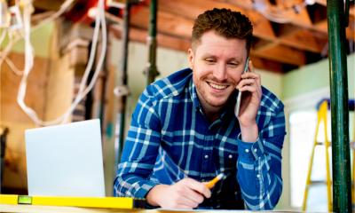 A tradesperson smiles whilst taking a phone booking for another job