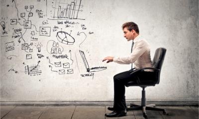 A man sits at a virtual desk in a virtual office